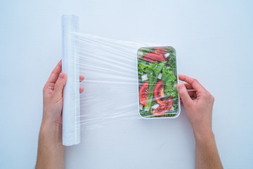 Using food polyethylene plastic film for food storage in fridge at home. Top view. Food protection
