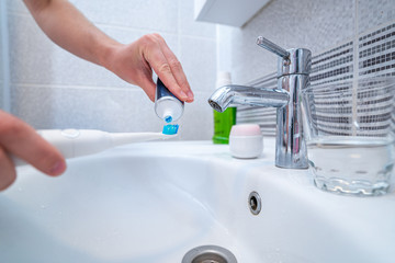 Ultrasonic toothbrush and using dental products for brush teeth and for fresh breath in bathroom at home. Oral hygiene, dental and gum health, healthy teeth. Daily life and routines