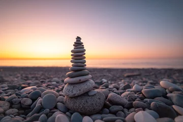 Stone pyramid on the background of sunset and sea on pebble beach symbolizing stability, zen, harmony and balance © Goffkein