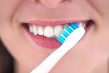 Brushing teeth with ultrasonic electric toothbrush close-up. Dental hygiene and teeth care