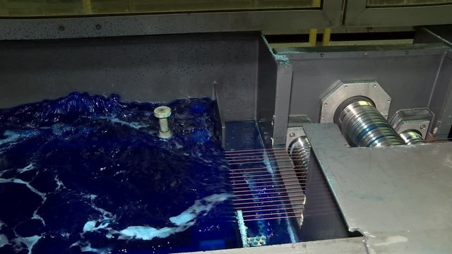 Production of wire by drawing technology. Wire production line by drawing method. Direct-flow drawing mill with program control. A container with a blue liquid for copper-plating wire.