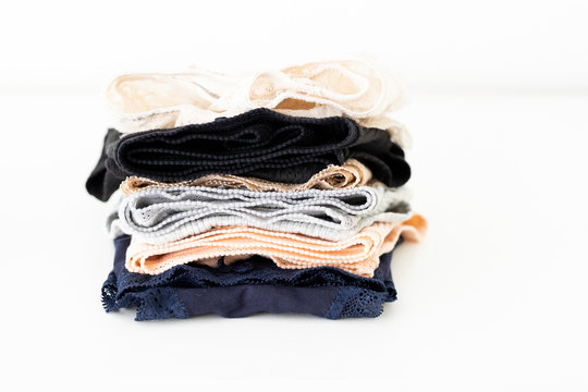 Stack of folded sexy women's panties on white table. Female underwear background. Copy space