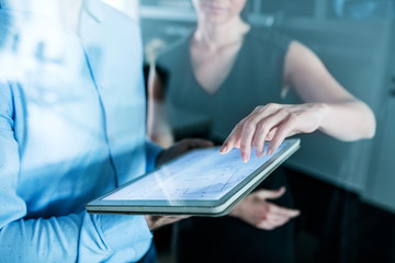 Midsection of young businesspeople with tablet in an office, working.