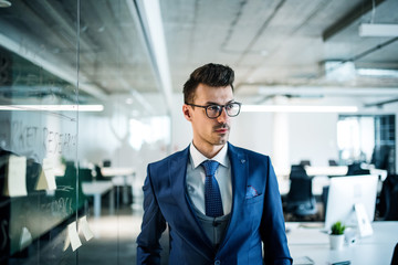 A portrait of young businessman walking in an office.