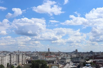 City landscape: houses, construction cranes, high sky, white clouds.