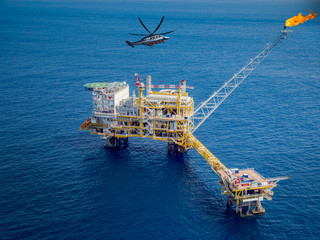 Offshore oil and gas rig platform with offshore helicopter transporting to oil rig at in the gulf...