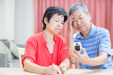 elder couple measure blood glucose