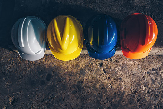 Safety helmet, white, yellow, blue and orange, placed on the cement floor in the construction site.