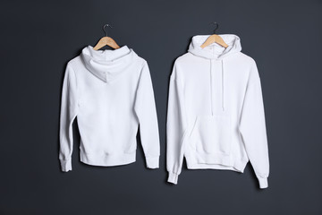 Hangers with new sweaters on dark wall, mock up for design