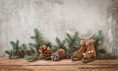 Christmas tree branches with cones on a dark wooden Board against a gray concrete wall.