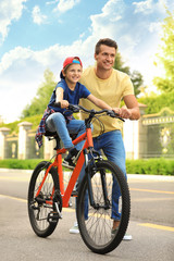 Obraz premium Dad teaching son to ride bicycle outdoors