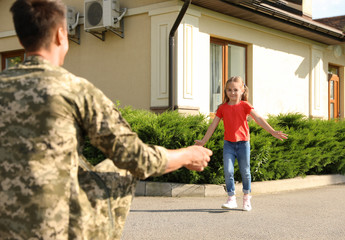 Fototapeta premium Father in military uniform and little daughter running to him outdoors