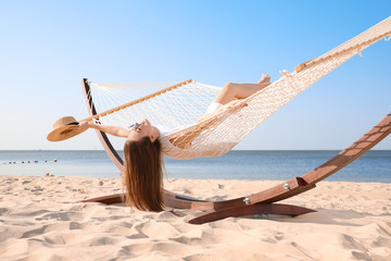 Young woman relaxing in hammock on beach