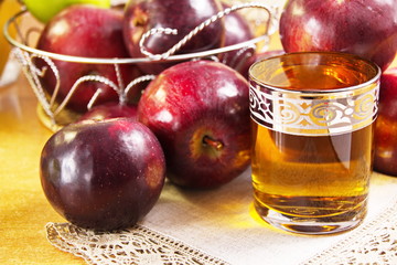 Apple juice clarified in a glass and fresh red apples