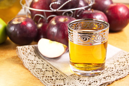 Apple juice clarified in a glass and fresh red apples
