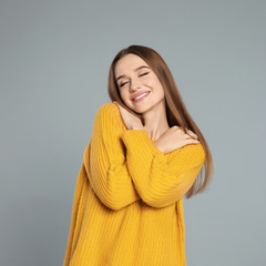 Beautiful young woman in yellow sweater on grey background. Winter season