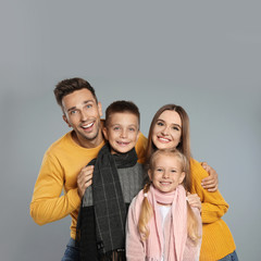 Fototapeta premium Happy family in warm clothes on grey background. Winter season