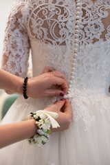 Girlfriend buttons bride wedding dress. Bride puts on a wedding dress. 