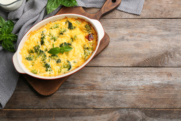 Flat lay composition with tasty broccoli casserole on wooden table. Space for text