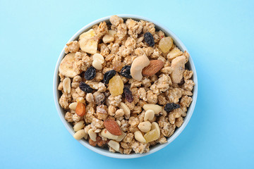 Bowl with healthy granola on light blue background, top view