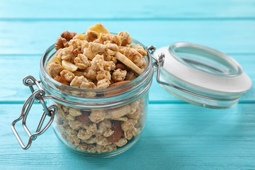 Jar with healthy granola on light blue wooden table