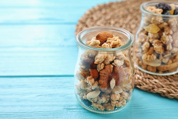Jars with healthy granola on light blue wooden table. Space for text