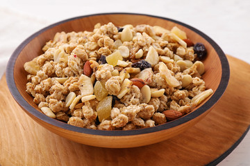 Bowl with healthy granola on wooden plate, closeup
