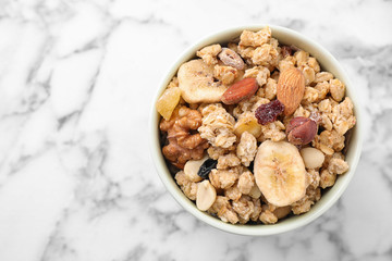 Bowl with healthy granola on marble table, top view. Space for text