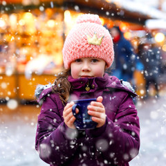Little cute kid girl with cup of steaming hot chocolate or children punch. Happy child on Christmas...