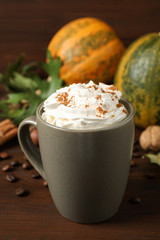 Cup with tasty pumpkin spice latte on wooden table