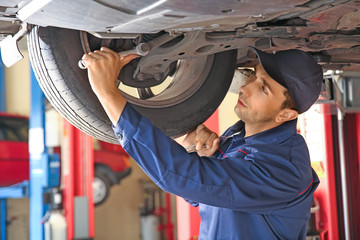 Male mechanic repairing car in service center