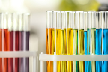 Test tubes with color liquids on blurred background, closeup view