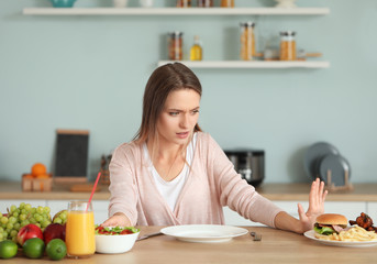 Woman refusing to eat unhealthy food in kitchen. Diet concept