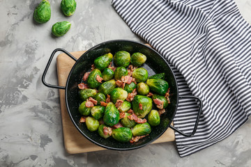 Tasty roasted Brussels sprouts with bacon on light grey table, flat lay