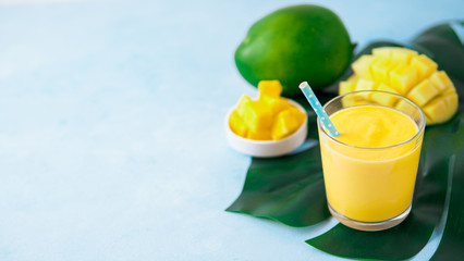 Yellow mango yogurt or smoothie on blue background with copy space left. Turmeric Lassie or lassi...