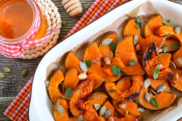 Pumpkin slices baked in the oven with honey, nuts, cinnamon, seeds, mint. Pieces of pumpkin lying...
