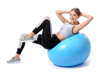 Sporty young woman training with fitball against white background