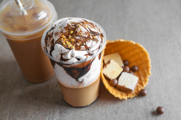 Cups of tasty frappe coffee and sweets on table