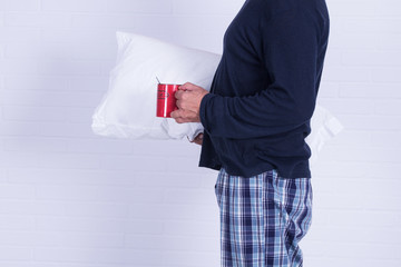 man in pajamas and pillow with his cup of coffee isolated