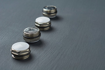 Row of four stubs in form of hexagon metal nuts with white plastic caps and rubber rings for bimetallic or aluminum radiator for heat room lies on dark concrete desk in workshop. Space for text