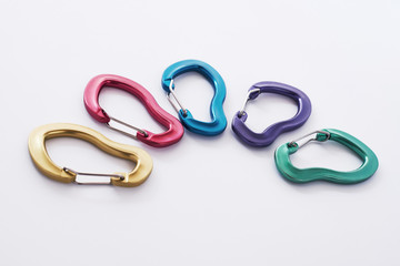 Many of the multi colored carabiners on lying on the white table