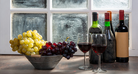 Composition with two wineglasses, grapes and bottles of red wine