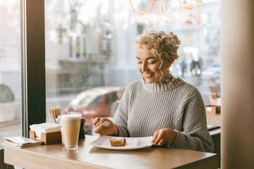 Woman drinking coffe by the window in city street cafe