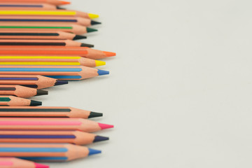 Colored pencils come from the left in a white background