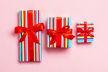 Gift box with red bow for Christmas or New Year day on pink background, top view
