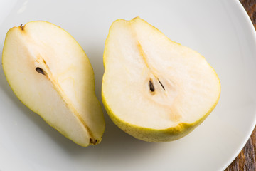 half and a quarter of a yellow pear on a white plate