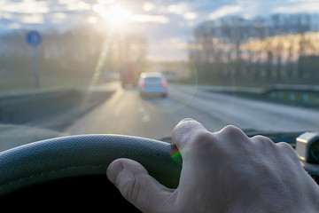 hand of a man on the steering wheel of a car that passes on the highway against the background of...