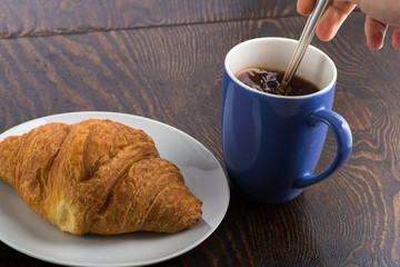 croissant on a white plate and coffee in a purple mug