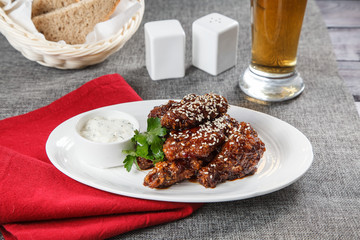 fried chicken wings with sesame seeds and sauce on a plate in a restaurant