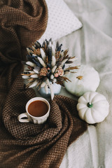 Coffee cup with flowers and pumpkins on a cozy plaid. Autumn still life. Breakfast in bed. Good morning. Stylish autumn flat lay. 